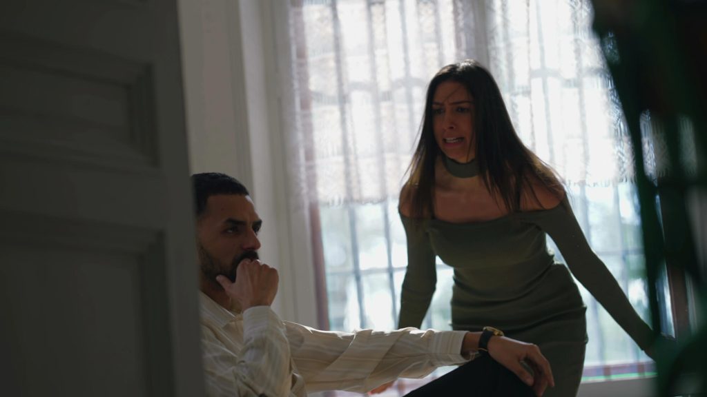 תמונת נושא של המאמר על תלונת שווא על אלימות במשפחה בה רואים אישה צועקת בכעס על גבר שנראה שקוע במחשבות בבית